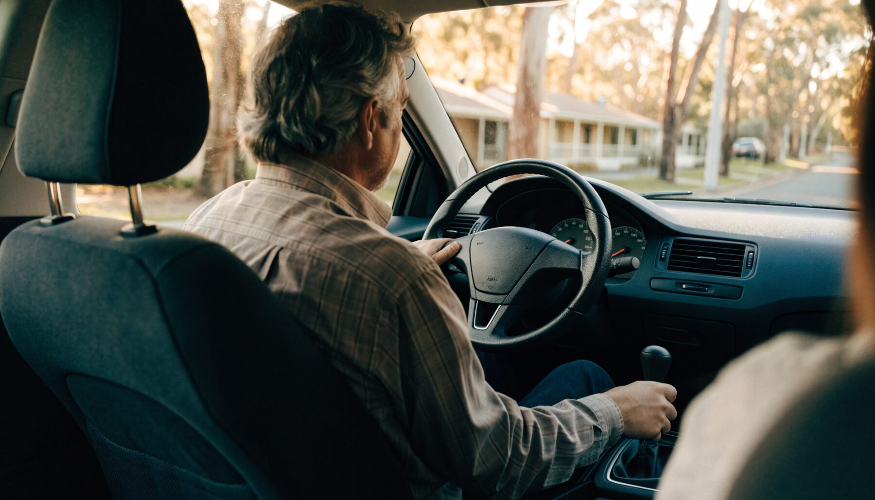 Driving instructor guiding a learner through gear changes during a manual driving lesson on a Melbourne suburban street